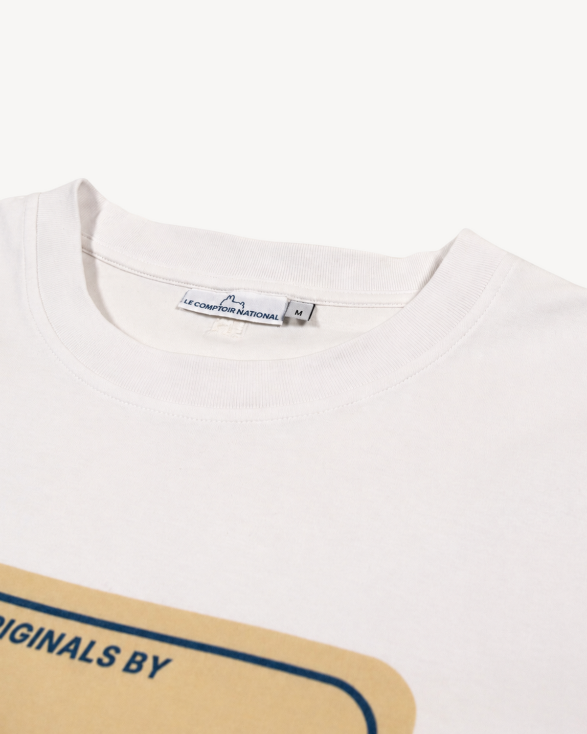 Gros plan sur le col rond en coton bio blanc cassé Cloud Dancer du t-shirt Le Comptoir National avec étiquette